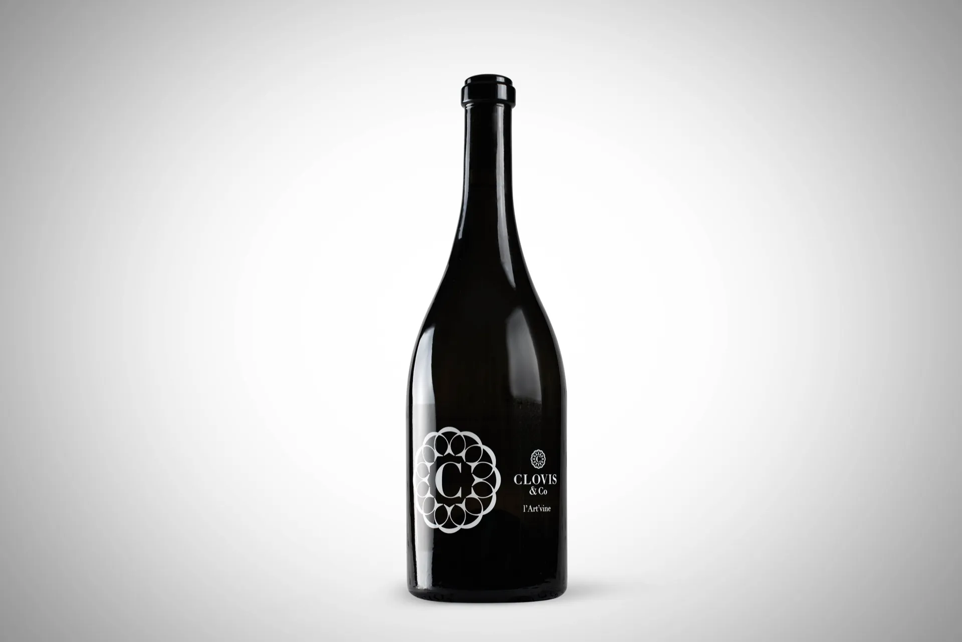 Bouteille de vin en verre clair sur fond neutre, packshot studio pour Clovis & Co